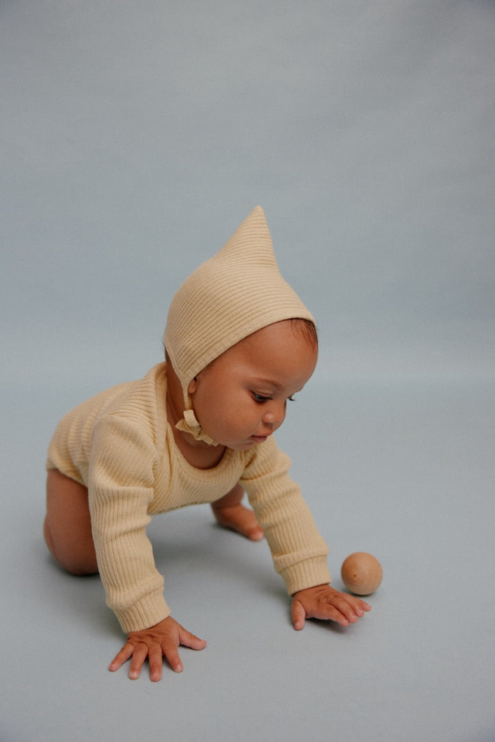 Baby wearing butter yellow pixie bonnet
